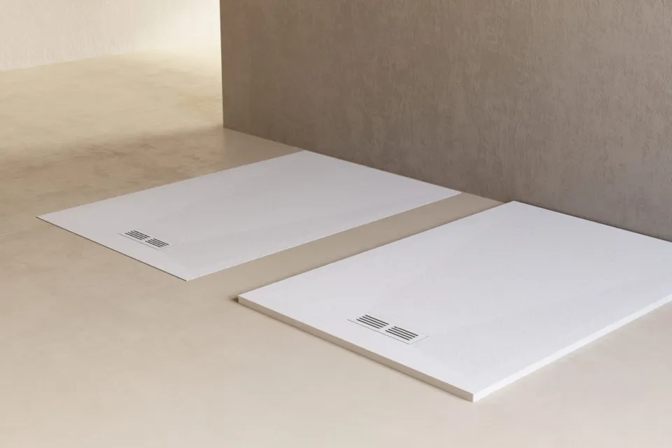 two white stone-finish shower trays